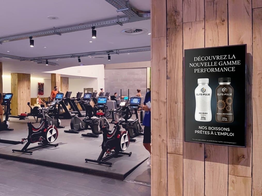 Un écran publicitaire sur le mur d'une salle de sport